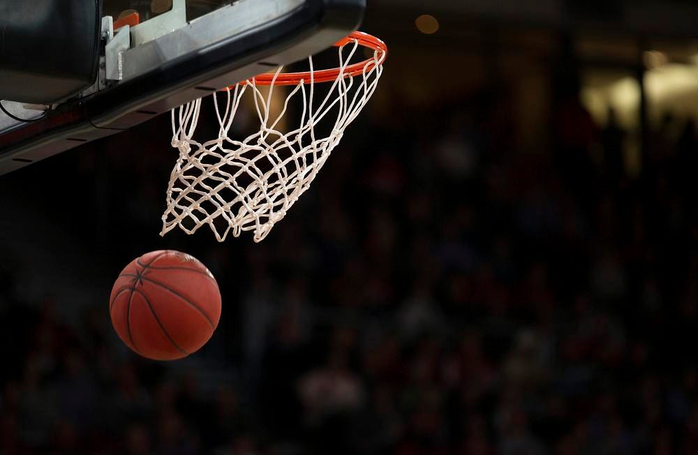 A basketball passes through the net as a player swishes the score during a basketball game