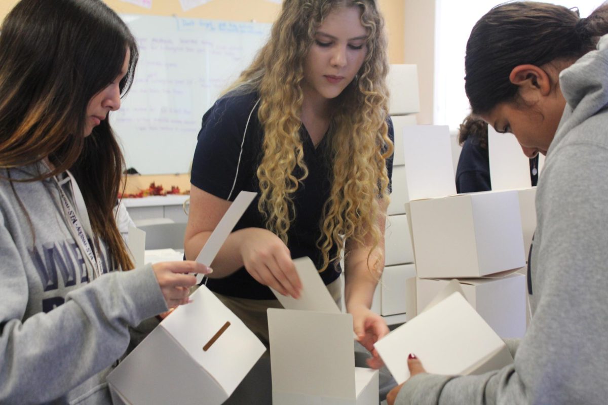 Students volunteer making boxes for C.A.R.E. Club.