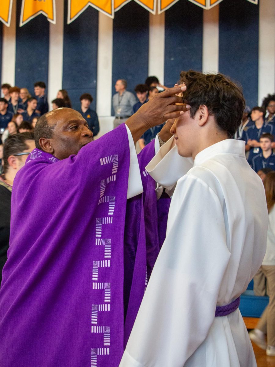 Father Celsus places ashes on the forehead of a member of campus ministry.